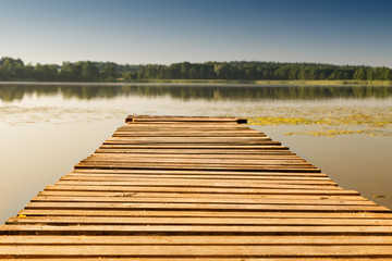 Obraz premium Empty footbridge on a lake. Summer background.