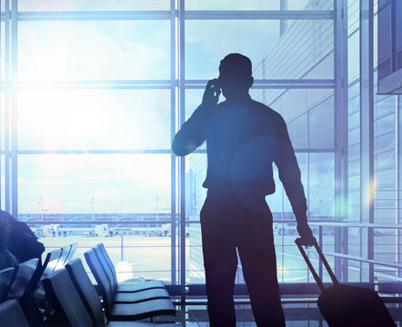 Gesch&auml;ftsreisender mit Koffer telefoniert im Flughafen