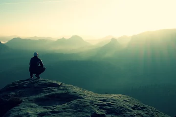 Foto auf Acrylglas Hiker sits on a rocky peak and enjoy the mountains scenery © rdonar