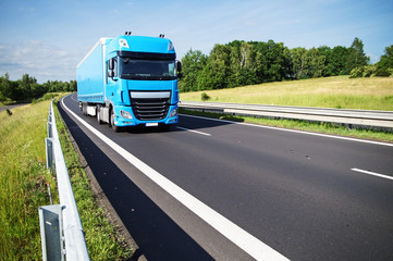 Fototapeta na wymiar Blue truck on asphalt expressway in the countryside