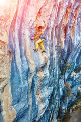 Naklejka na ściany i meble Rock climber climbing up a cliff