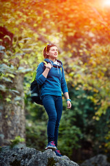 Woman hiker smiling standing outside in forest with backpack