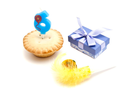cupcake with six years birthday candle, gift and whistle on whit