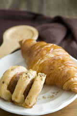 sausage roll on dish with croissant