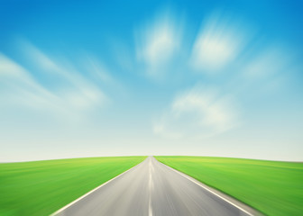 Asphalt road through the green field and blue sky