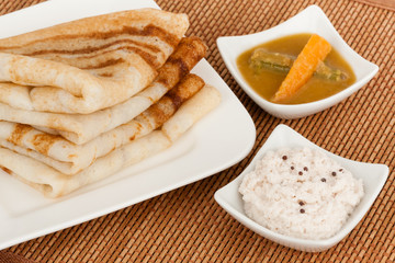 Traditional south Indian breakfast of Dosa (Dosai) stack served with coconut chutney and sambar.