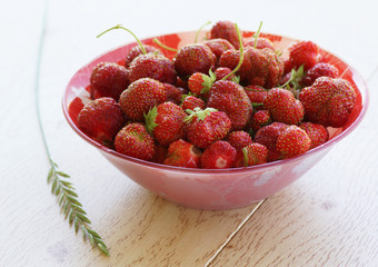 Strawberries in a plate on a wooden surface.