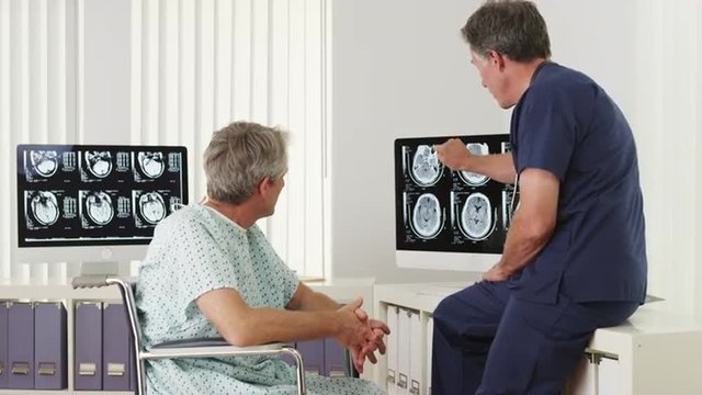 Mature doctor explaining xrays to disabled elderly patient