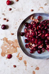 cutting in half juicy cherries on a round tray on marble surface
