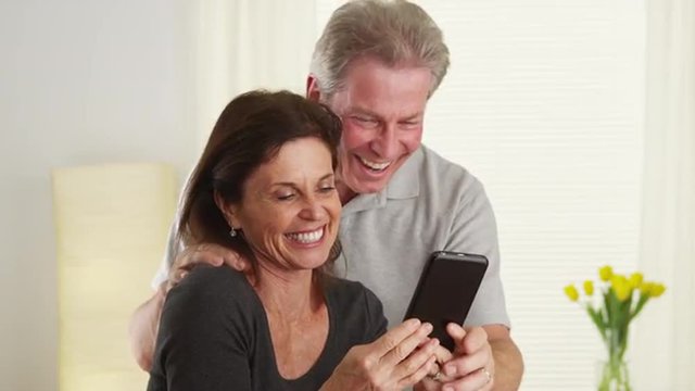 Senior couple laughing and using new smart phone