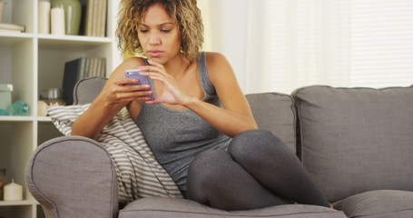 Black woman using smartphone on couch