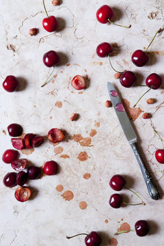 cutting juicy fresh cherries on marble surface with a knife