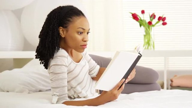 Black woman reading on bed