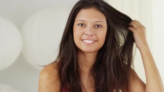 Attractive Hispanic woman playing with hair and smiling at camera