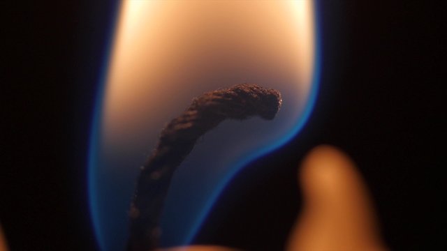 Man lites a wax candlestick in dark room