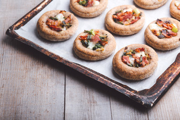 Mini pizzas on a baking paper in a pan