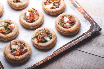 Mini pizzas on a baking paper in a pan