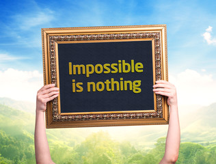 Female hand holding a card with the text: Impossible is nothing
