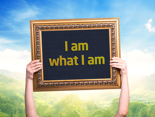 Female hand holding a card with the text: I am what I am
