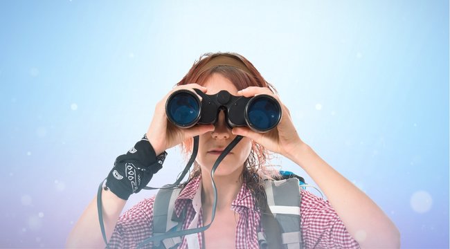 girl looking through binoculars over white background