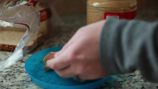 man prepares a peanut butter sandwich
