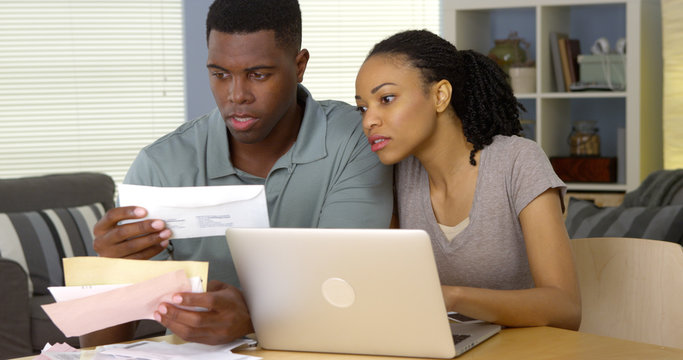 Serious Young Black Couple Paying Bills Online With Laptop Computer