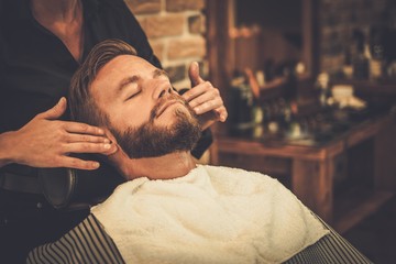 Hairstylist applying after shaving lotion in barber shop - Powered by Adobe