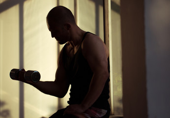 Obraz premium Man lifting free weights in the gym - silhouette