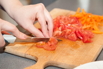 Closeup of cutting fresh tomatoes on wooden board