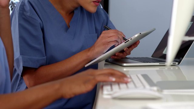 Close up hands of two female doctors working with computers