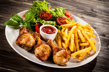 Grilled chicken legs with chips and vegetables 