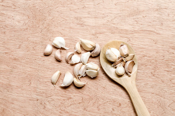 garlic cloves on wooden spoon and scattered on the wooden floor