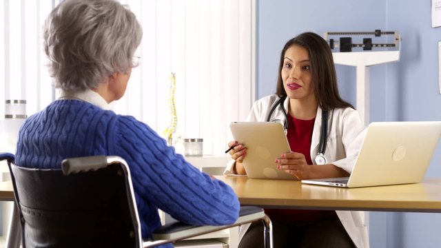 Mexican woman doctor talking with elderly patient