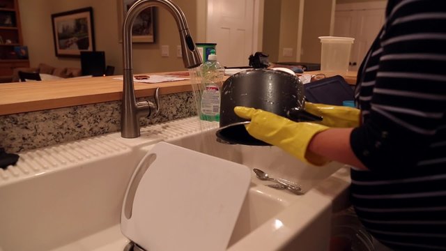 a pregnant mother washing dishes at the kitchen sink