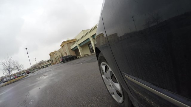 Car driving through parking lot at strip mall
