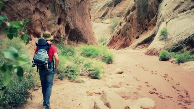 father and baby walking in a deep desert slot canyon