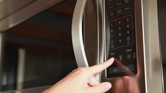 a woman using the timer on the microwave