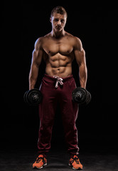 Portrait of a muscular man lifting weights against a dark backgr