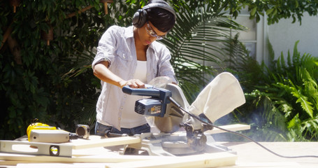 Black woman doing home improvement cutting wood with a table saw