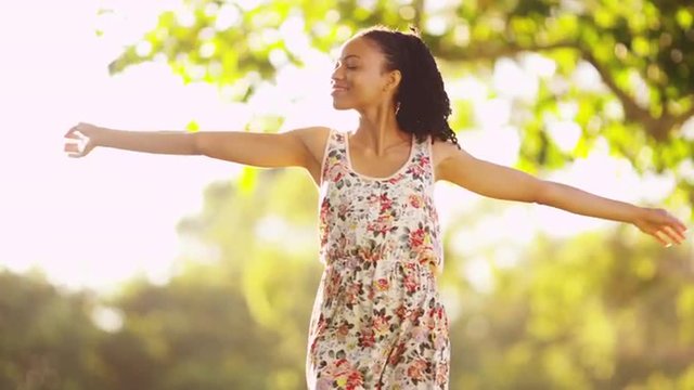 Attractive African woman twirling around in a park