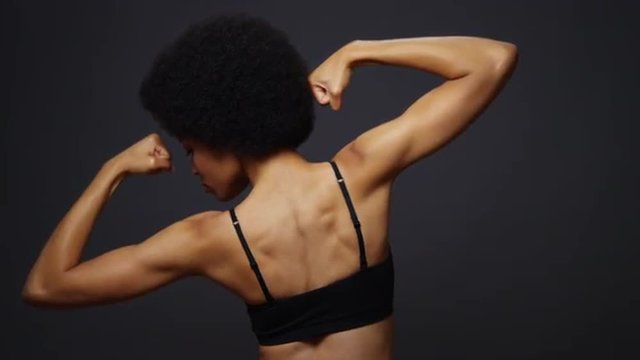 Rear view of Black woman flexing muscles