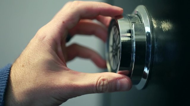 hand opening a combination lock on a safe
