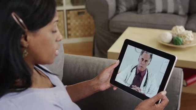 Senior african patient listening to doctor talk on tablet