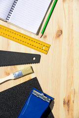 Workplace and tools of a carpenter or builder.Hand saw, ruler, brush, notebook, pencil, sandpaper, and work gloves