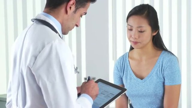 Hispanic doctor asking Asian patient questions
