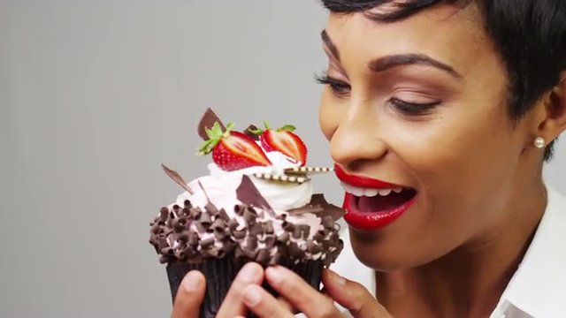 Black woman taking a huge bite out of a fancy dessert