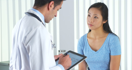 Hispanic doctor asking Asian patient questions