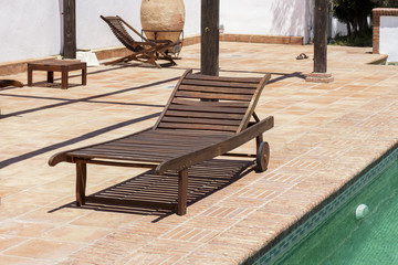Wooden sun recliner beside a swimming pool