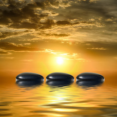 Fototapeta na wymiar Zen spa concept background-Zen black massage stones reflected in water