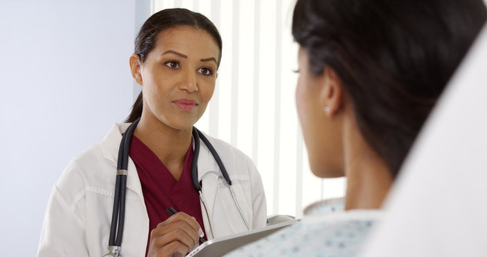 Over The Shoulder Shot Of African American Doctor Talking To Female Patient